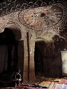 Interior of a rock-hewn church with painted walls and ceiling