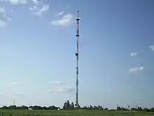 Tall communications tower on flat ground, with guy wires