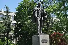 Statue of man in cape on a pedestal in front of a building