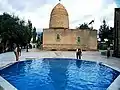 A view of the exterior of the mausoleum, with a swimming pool in the foreground.