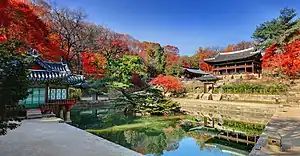 A small colorful wooden pavilion on a pond covered with lotus leaves