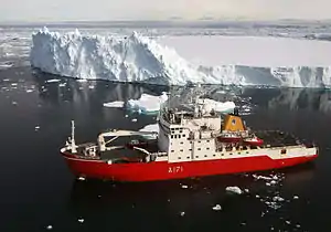 An overhead view of HMS Endurance coloured bright red. About 100 metres from her are icebergs, coloured white. The sea is calm, and a deep blue.