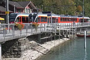 Two red-and-white trains on tracks next to quay