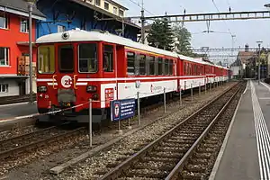 Red-and-white train on double-track railway line surrounded by side platforms