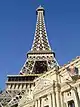 Ground-level view of a steel tower; the tower is broad at its base, rising from four separate legs. It then tapers, with each leg meeting to form a single, latticework column. Three platforms are visible at various heights up the side of the structure.