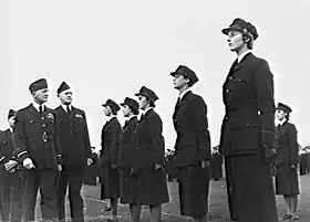 Three men and six women in dark-coloured military uniforms, outdoors