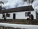 This oblong, thatched house without a front gable is situated on land which was sold by the local church to a widow, Mrs S. W. van der Merwe, and her son in 1853. The house probably dates from an earlier period. Type of site: House Previous use: Residential. Current use: House.