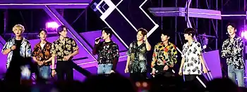 Exo standing on stage talking to the crowd at a festival in 2018.