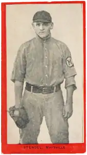 a young man in an old-style baseball uniform wears a glove and stares at the camera