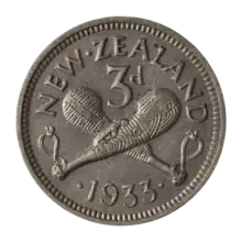 A silver coin with two crossed patu clubs, with the label "3D" above them. Below is the date, 1933, and arcing above is the text "NEW ZEALAND".