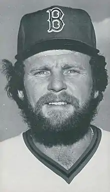 A man in a light baseball jersey and dark cap