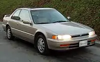  Front three-quarter view of a two-door car with a three-box body style fitted with a sunroof and rear spoiler.