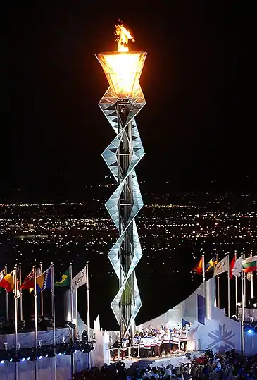 Interwoven steel frame several stories high with the lit flame at the top