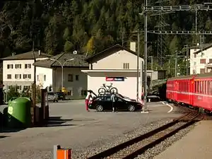 Red train at two-story building with gabled roof