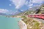 A train running through a snowy mountain valley.