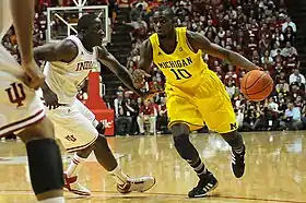 Player dribbling, guarded by two players in white uniforms