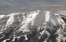 A snowcapped mountain with two clusters of communications towers at its peak