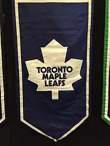 A banner featuring an old Maple Leaf logo, featuring an eleven-pointed white maple leaf on a blue background.