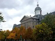 A photo taken in 2019 of the building that used to be the Montreal Institute for the Deaf and Mute partially obstructed by trees as seen from rue Saint-Denis.