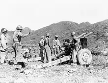 A group of men standing around a large gun