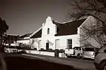 Thatched 5-bay Cape Dutch house with mock-chimney end gable, attached to No. 38. Wide holbol gable with semicircular pediment and blocked-up window. 3 × 3 double door with geometric fanlight, c 1850 (F & C), 2 × 2 sashes. Full-length hipped verandah on p Type of site: House Current use: House. This house with its fine gable was built in 1860 and is a good example of Nineteenth Century Architecture in Worcester.