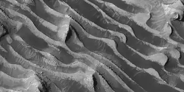 Close-up of layers, as seen by HiRISE.  Boulders are visible, as well as dark sand.