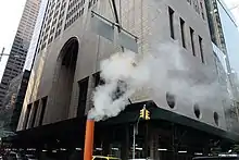 The northeast corner of 550 Madison Avenue as seen from ground level. There is a steam funnel on the street in front of the facade.