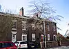 A terrace of three two-storey houses, each with a doorway flanked by columns, above which is a fanlight