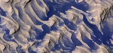 Close, color view of layers and dark dust on floor, as seen by HiRISE.  Boulders are visible in the image.