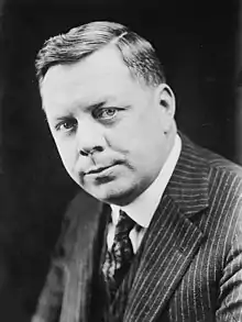 Black and white portrait of a man, wearing a suit, collared shirt, and tie