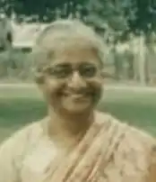 A smiling middle-aged South Asian woman, wearing a sari.