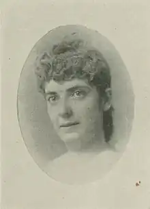 B&W oval portrait photo of a woman with her hair in an. up-do, wearing a white blouse.