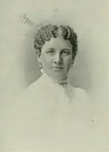 B&W portrait photo of a woman with her hair in an up-do, wearing a white, high-collared blouse