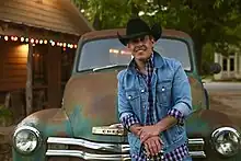 Country singer Aaron Watson posing in front of a pickup truck