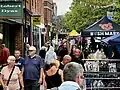 A market trader waves from the crowd and to the camera on St Albans Market.