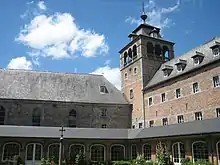 Le cloître de l'abbaye de Leffe et, à son angle, la tour clocher (photographie moderne).