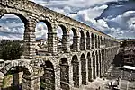 A three-storied aqueduct running through a town.