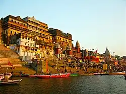 Ganges riverfront with steps, temples, people, and boats