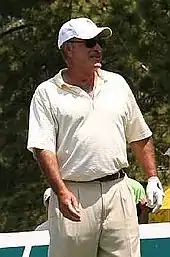 Knee high portrait of a man wearing khaki colored clothes and wearing a baseball hat