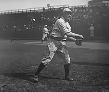 A black-and-white image of a man in a white old-style baseball uniform