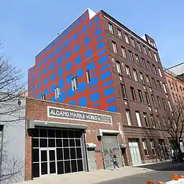 a one story building next to a seven story building which has a large mural across its side