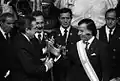 President Raúl Alfonsín gives the presidential sash and staff to President–elect Carlos Menem in 1989