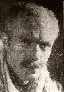 Newsprint photograph of a middle-aged man with a long face, short hair and moustache