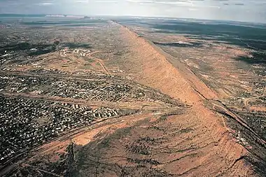 An expansive plain with a large mountainous ridge running through it along a curved line