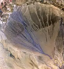 A 60 km long Megafan across the desolate landscape between the Kunlun and Altun mountain ranges that form the southern border of the Taklamakan Desert in Xinjiang. The left side is the active part of the fan, and appears blue from water flowing in the many small streams