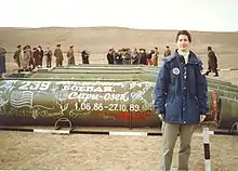 Woman in blue jacket stands before missiles