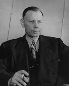 Half length portrait of sitting man in a suit and tie.