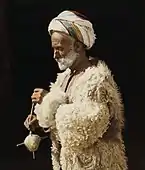 A man from Ramallah spinning wool. Hand tinted photograph from 1919, restored.