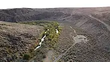 Drone image of the West Little Owyhee River at Anderson crossing. This image is from September, so the water is very low. Lush green plants flank the river for 10-20 feet on each side, then becomes sagebrush.