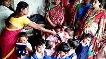 Anganwadi worker distributing dresses to children